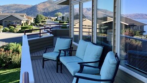 Una terrazza con posti a sedere all'aperto e ampie finestre che si affacciano su una zona residenziale e delle colline.