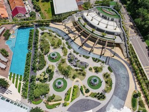 Vue aérienne d’un hôtel doté d’une piscine centrale, de jardins aménagés et d’un bâtiment de forme circulaire.