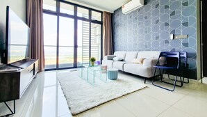 A modern living room with a sofa, a TV, a ceiling fan, and a large window offering a view of the outdoors. - Green Haven by Tove Global (Masai)