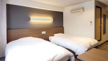 Ein Hotelzimmer mit zwei Einzelbetten, einem Holzkopfende, einer Wandklimaanlage und einer Tür mit Fenster.