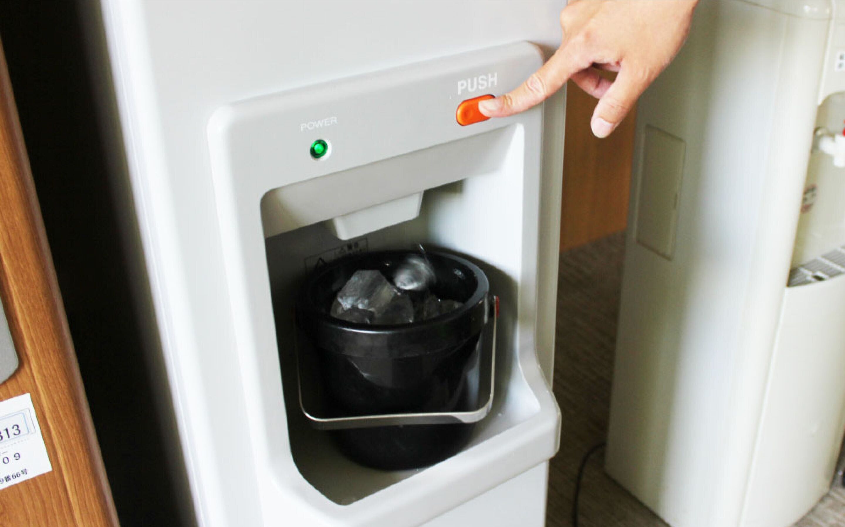 A water dispenser with a push button and a green indicator light.