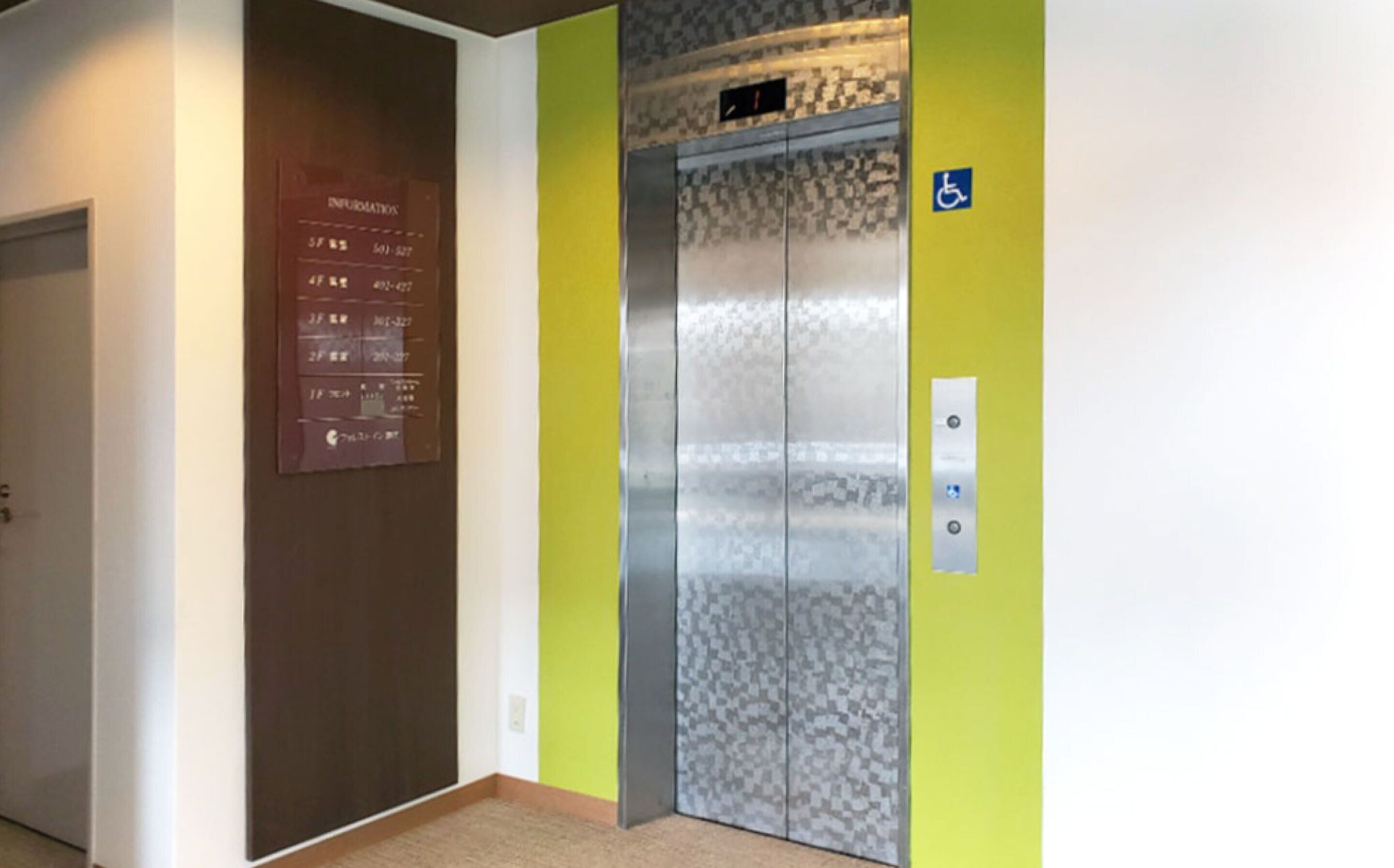 An elevator with a digital information panel and a wheelchair accessibility sign.