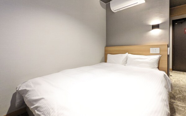 Een opgemaakt bed met witte lakens in een hotelkamer.