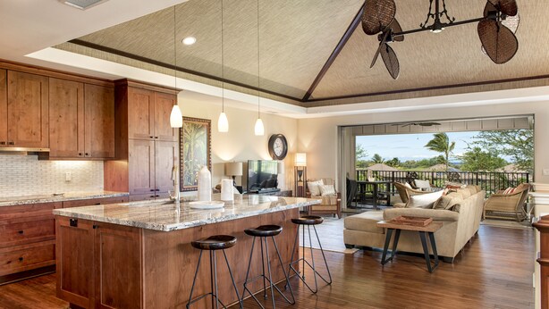 Una cocina amplia con una isla grande, armarios de madera y un comedor con sofá y sillas.