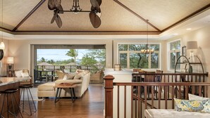 Un espacio habitable amplio con piso de madera, un balcón con vistas y una cocina con mesa de comedor y taburetes de bar.