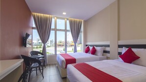 A hotel room with two beds, a desk, and a chair.