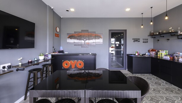 A modern kitchen with a central island, a dining area with wicker chairs, and a bar area with shelves.