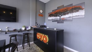 A modern reception area with a black counter, a mounted TV, a clock, and a series of framed landscape paintings.