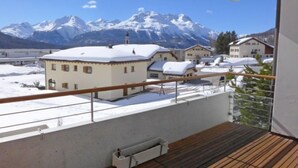 Een balkon met uitzicht op besneeuwde bergen en huizen.