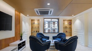 A modern living room with a TV, seating area, and built-in shelves. - Hotel Balmi (Yangon)