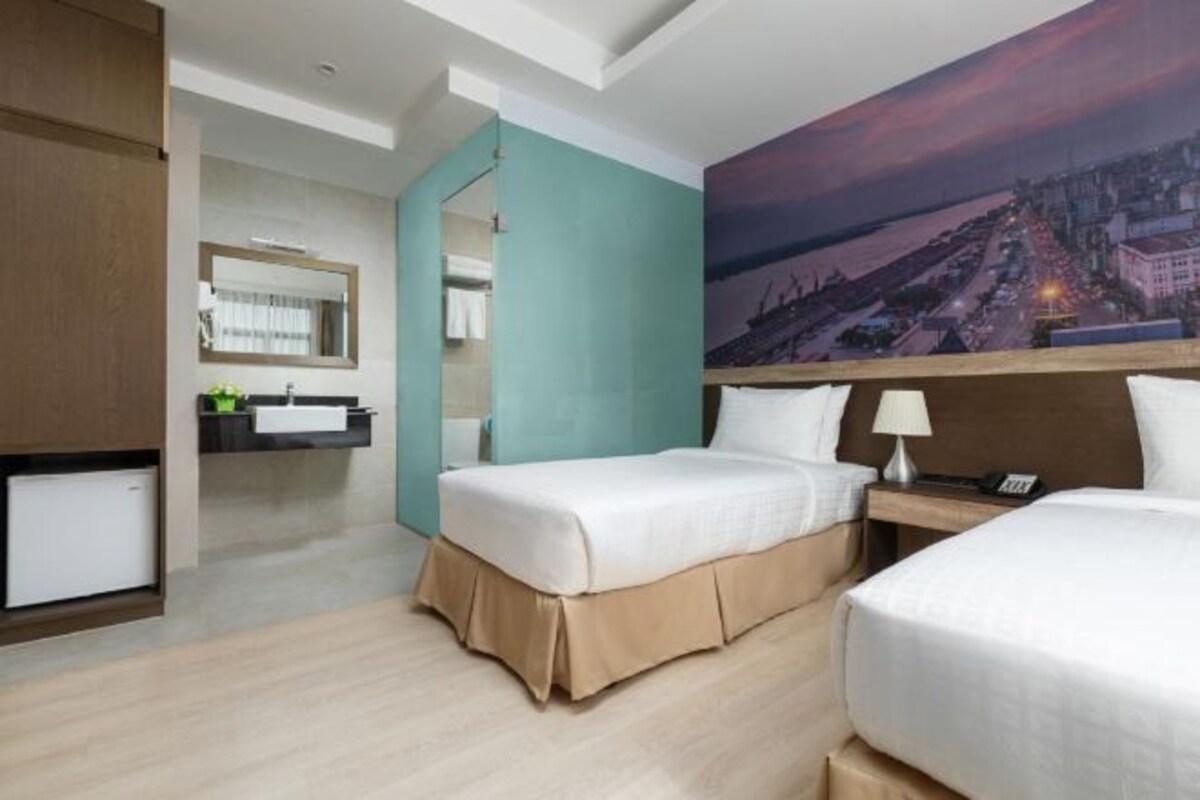 A hotel room with two beds, a bathroom, and a cityscape view.