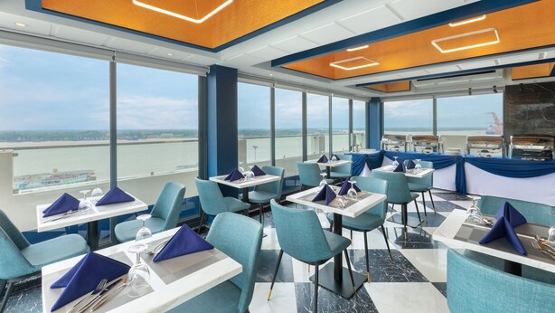 A modern restaurant with a view of the sea, featuring blue and white decor and a clean, contemporary layout. - Hotel Balmi (Yangon)