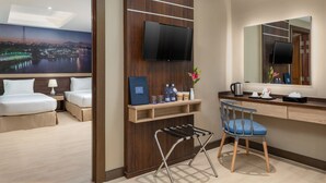 A hotel room with two beds, a desk, a chair, a TV, and a large mirror. - Hotel Balmi (Yangon)