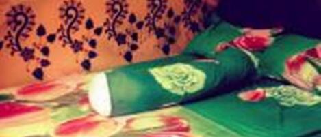 A bed with green bedding and a floral pattern, a dark headboard, and a wall with a decorative border.