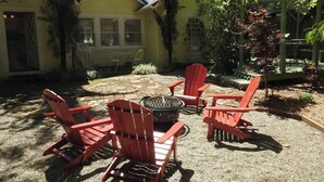 Un'area patio con quattro poltrone Adirondack rosse disposte attorno a un braciere circolare.
