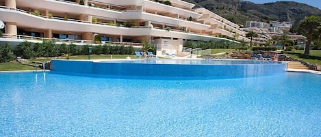 Un hôtel doté d’une grande piscine, de nombreux balcons et offrant une vue sur un paysage montagneux.