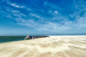 A beach with a boat docked on the sand, a clear sky, and a calm sea.