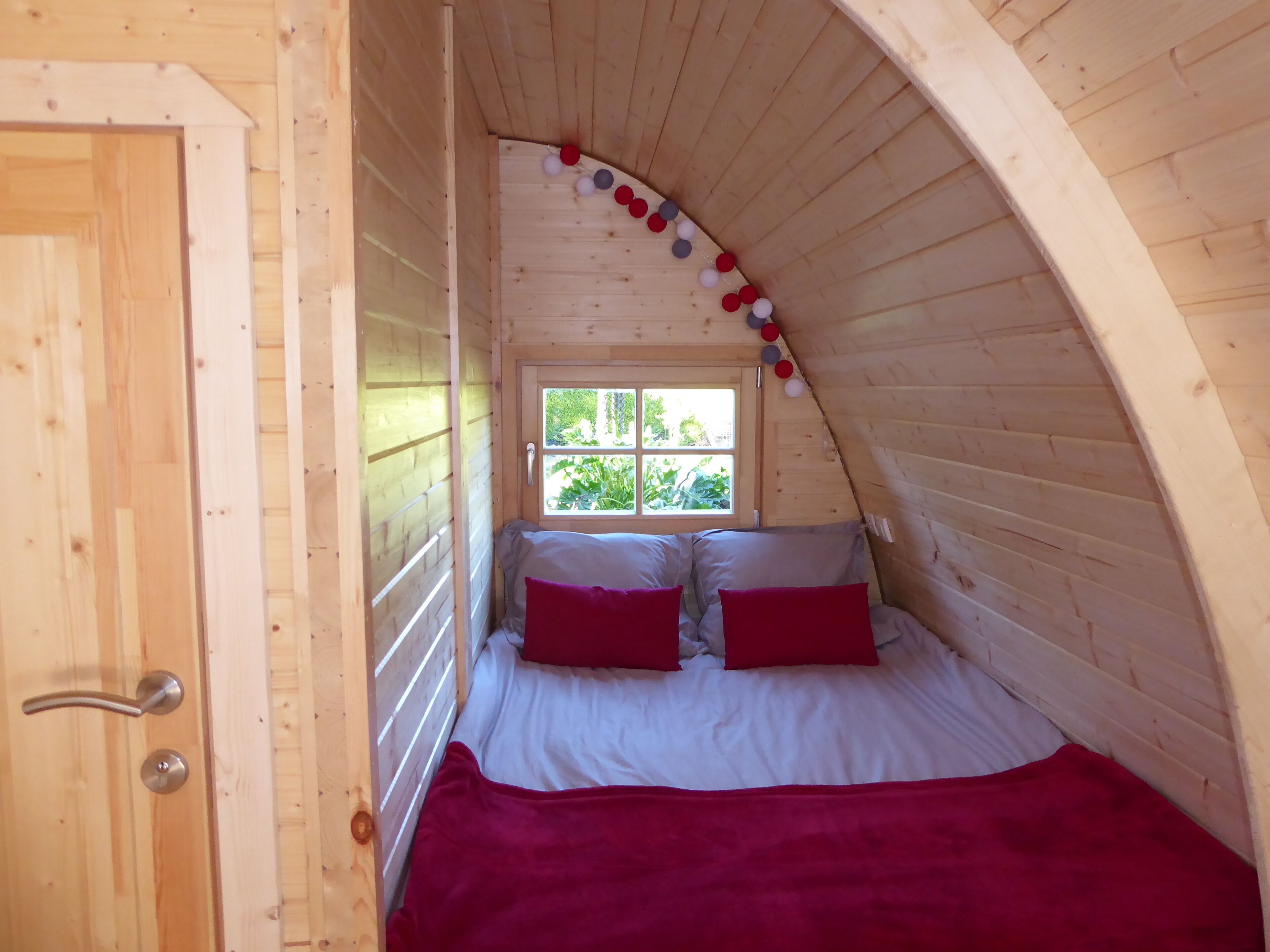 A small, cozy bedroom with a sloped ceiling, a window, and a door.