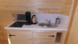 A compact kitchenette with a sink, coffee maker, and kettle.