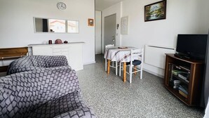 A compact room with a bed, a desk, a chair, a TV, and a bookshelf. - Studio in Cambo-les-Bains, balcony, parking, sleeps 2 (Cambo-les-Bains)