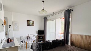 A hotel room with a bed, a desk with a chair, a television, and a window with curtains. - Studio in Cambo-les-Bains, balcony, parking, sleeps 2 (Cambo-les-Bains)