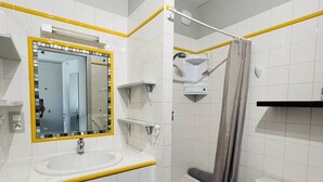 A bathroom with a white sink, mirror, and shower area. - Studio in Cambo-les-Bains, balcony, parking, sleeps 2 (Cambo-les-Bains)