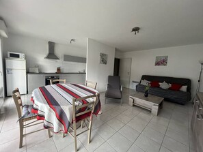 Espaço compacto com área de refeições, cozinha compacta e sofá-cama.