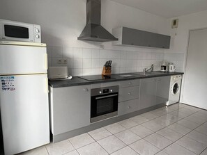 Fully equipped kitchen with a refrigerator, microwave, oven, and sink.