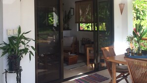 A modern interior with a sliding glass door leading to a balcony, wooden furniture, and potted plants. - Royal Palm Villas (Cóbano)