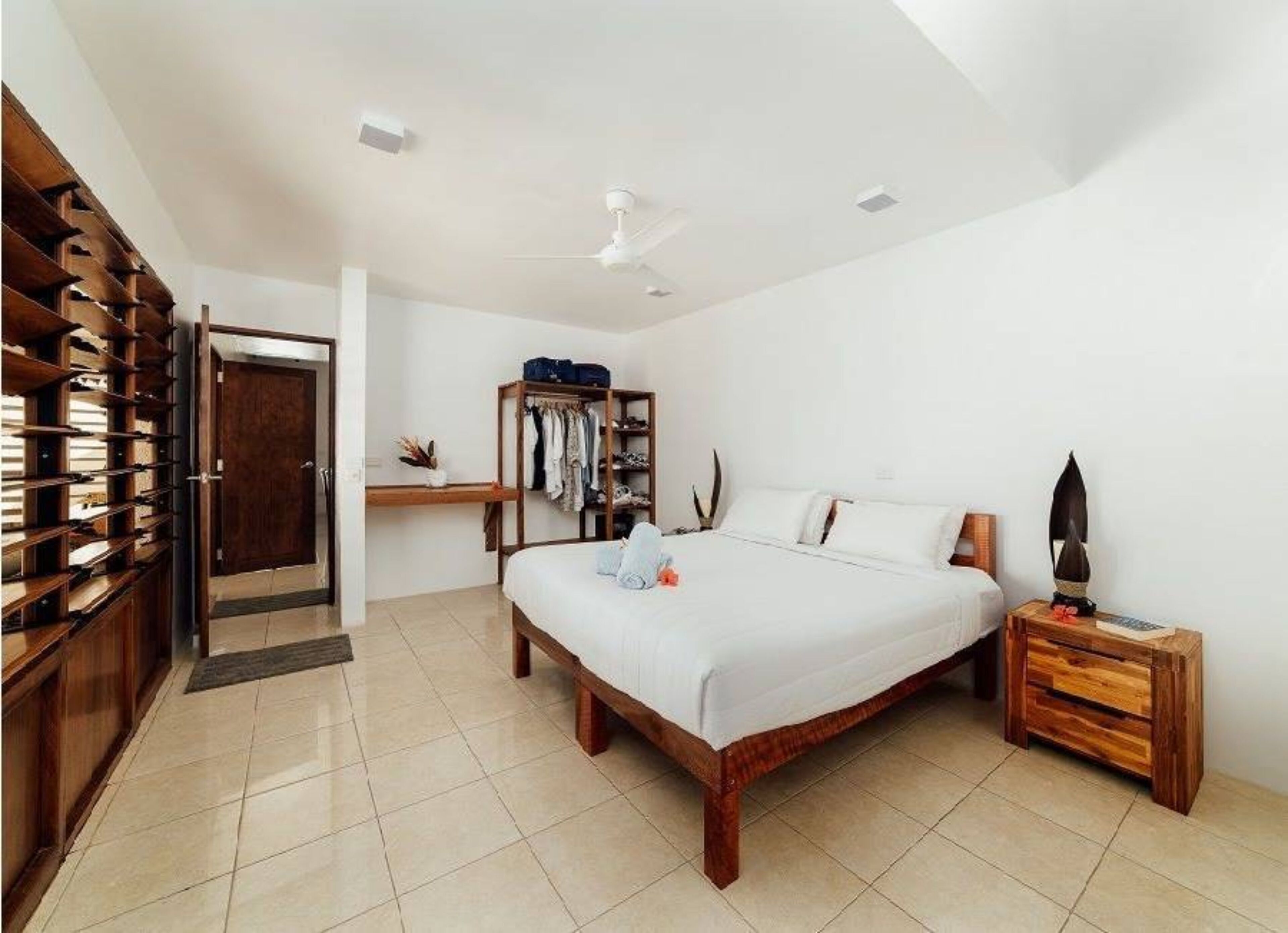 A bedroom with a wooden bed, a wardrobe, a desk, and a ceiling fan.