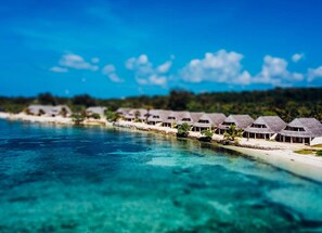Overwater bungalows with thatched roofs, a clear blue sea, and a tropical landscape. - Waves at Surfside (Port Vila)
