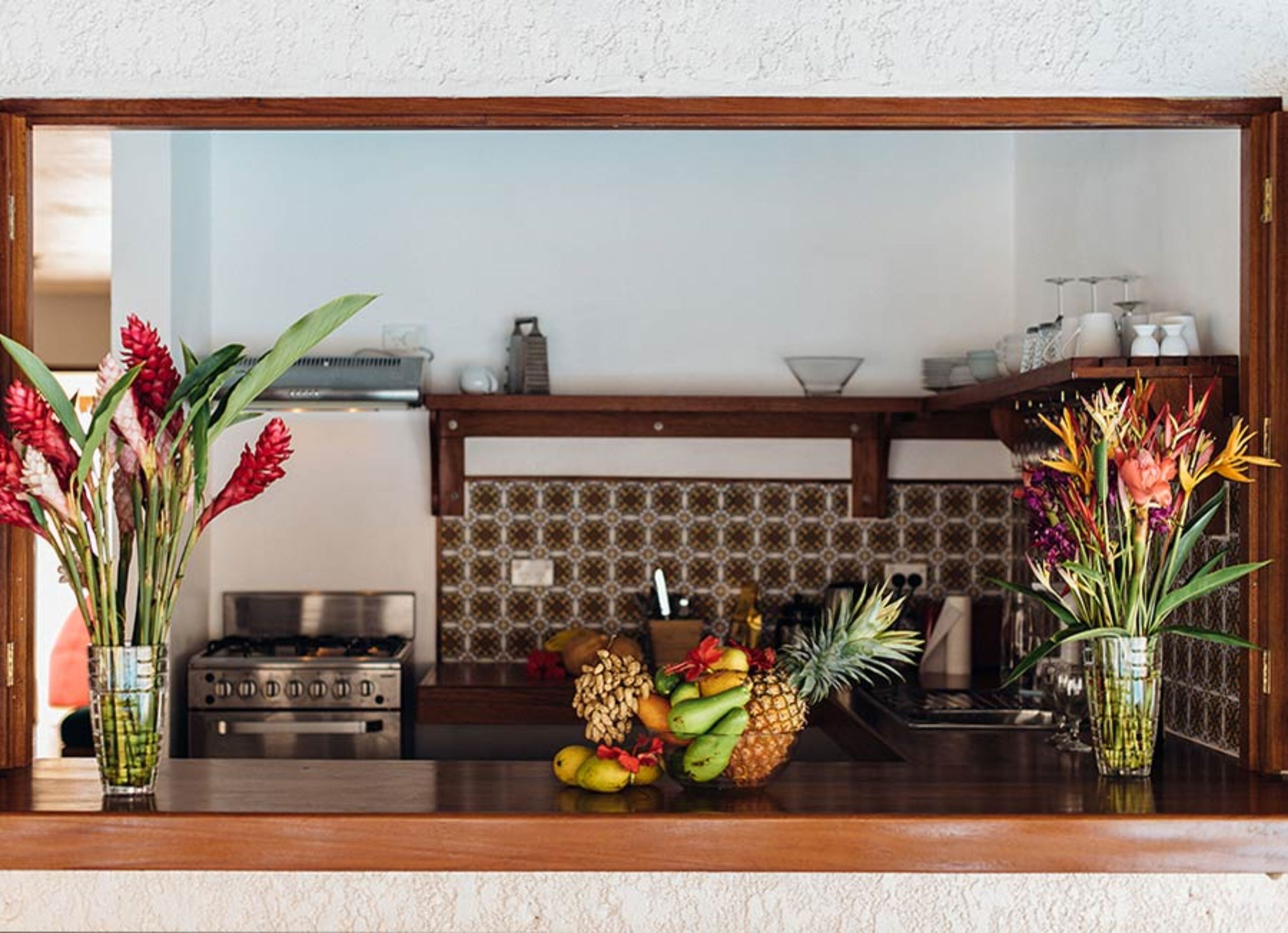 A kitchen with a tiled backsplash, a gas stove, and a fruit display on the counter.