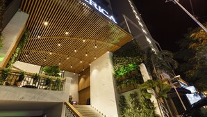 A modern hotel with a wooden slatted entrance canopy, a visible staircase, and a green wall with plants. - Erica Nha Trang Hotel (Nha Trang)