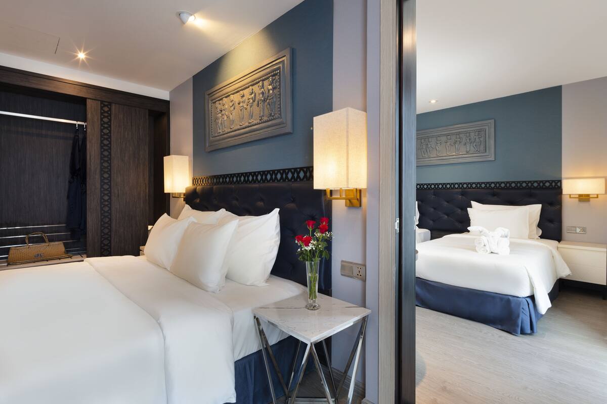 Ein Hotelzimmer mit einem großen Bett, einem kleinen Tisch mit Blumenvase und zwei Wandleuchten.