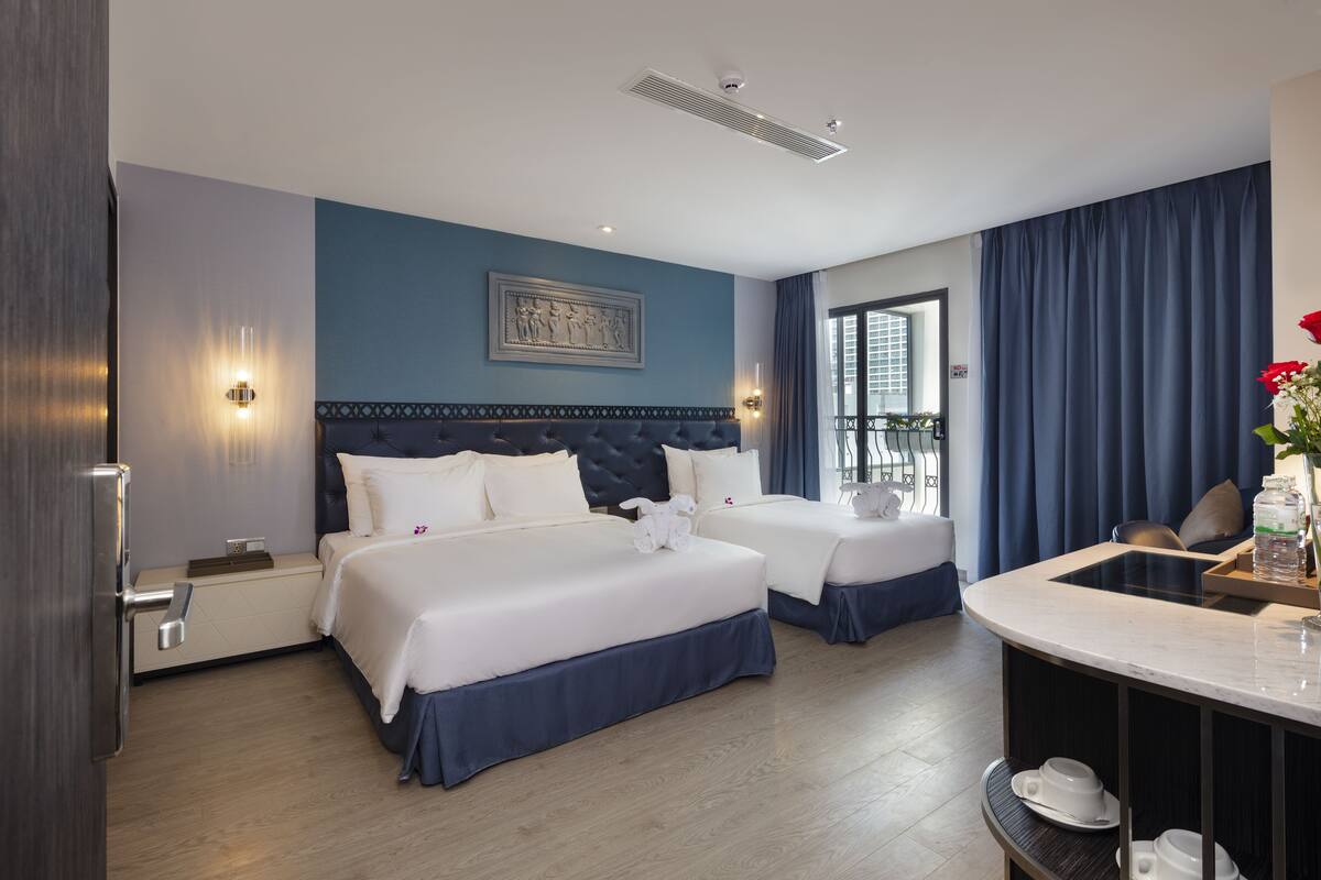 Ein Hotelzimmer mit zwei Betten, einem Schreibtisch und Blick auf die Stadt.