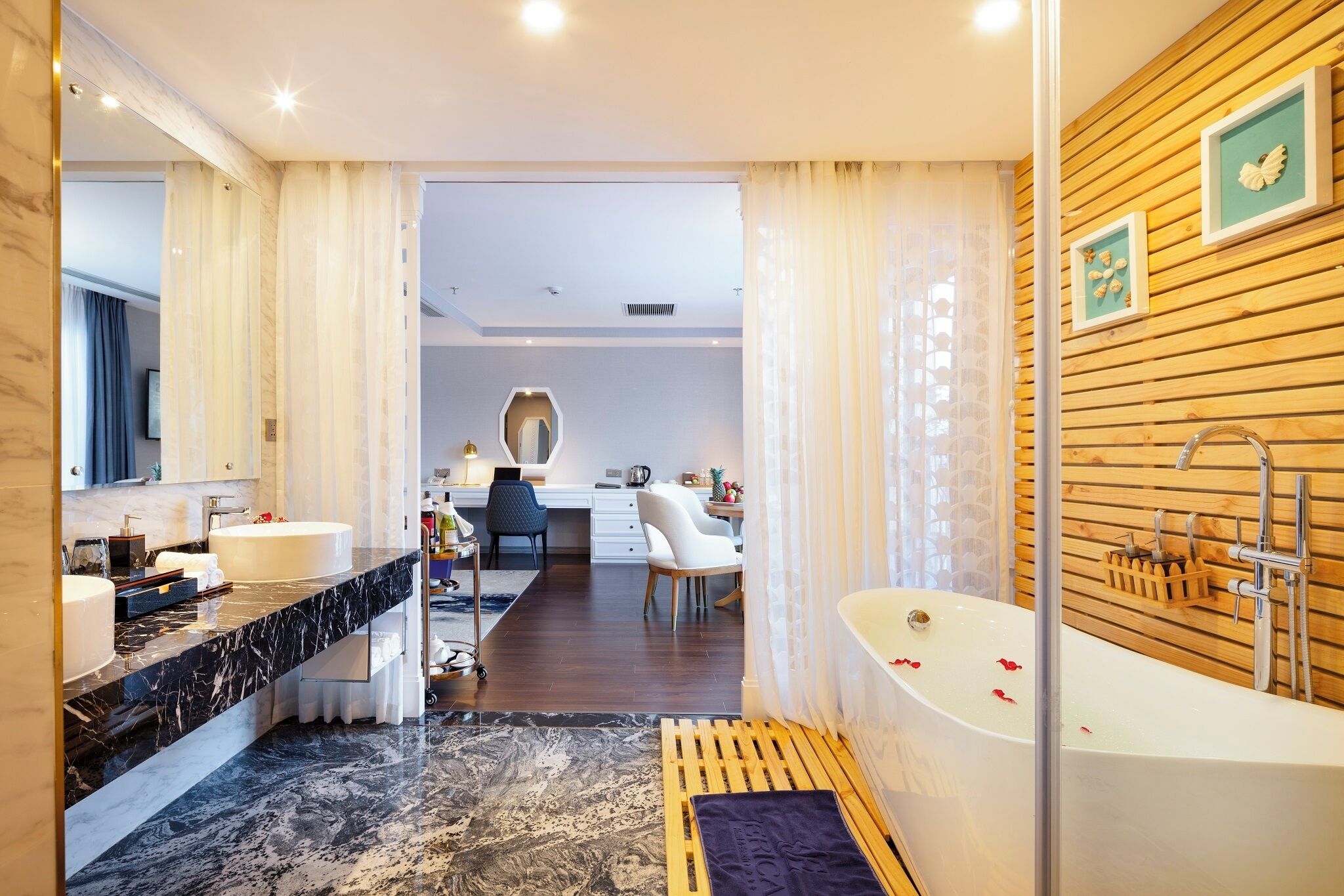 A modern bathroom with a marble vanity, a freestanding bathtub, and a wooden wall panel.