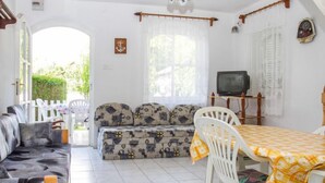 Un salon confortable avec un canapé, une table à manger et des chaises, un téléviseur et une fenêtre avec des rideaux.