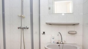 Une salle de bain avec une douche, un lavabo et un miroir.