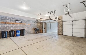 Garage features a brick wall, wooden shelf, and framed picture.