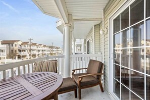 Enjoy the view from this balcony with a table and two chairs, overlooking a row of townhouses.