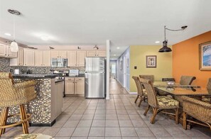 Enjoy meals in the kitchen with a central island and dining area featuring a table and wicker chairs.