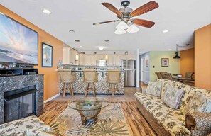 Relax in this stylish living space with a central kitchen island, sofa, coffee table, and fireplace.