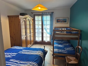 A bedroom with a bunk bed, a wooden wardrobe, a chair, and a window with curtains. - House in Vannes (Gulf of Morbihan) (Séné)