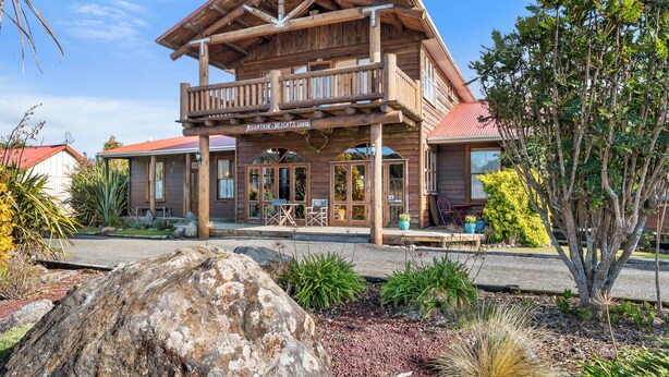 Un chalet en bois doté d’un balcon, d’une terrasse couverte et d’une enseigne indiquant « Mountain Heights Lodge ».