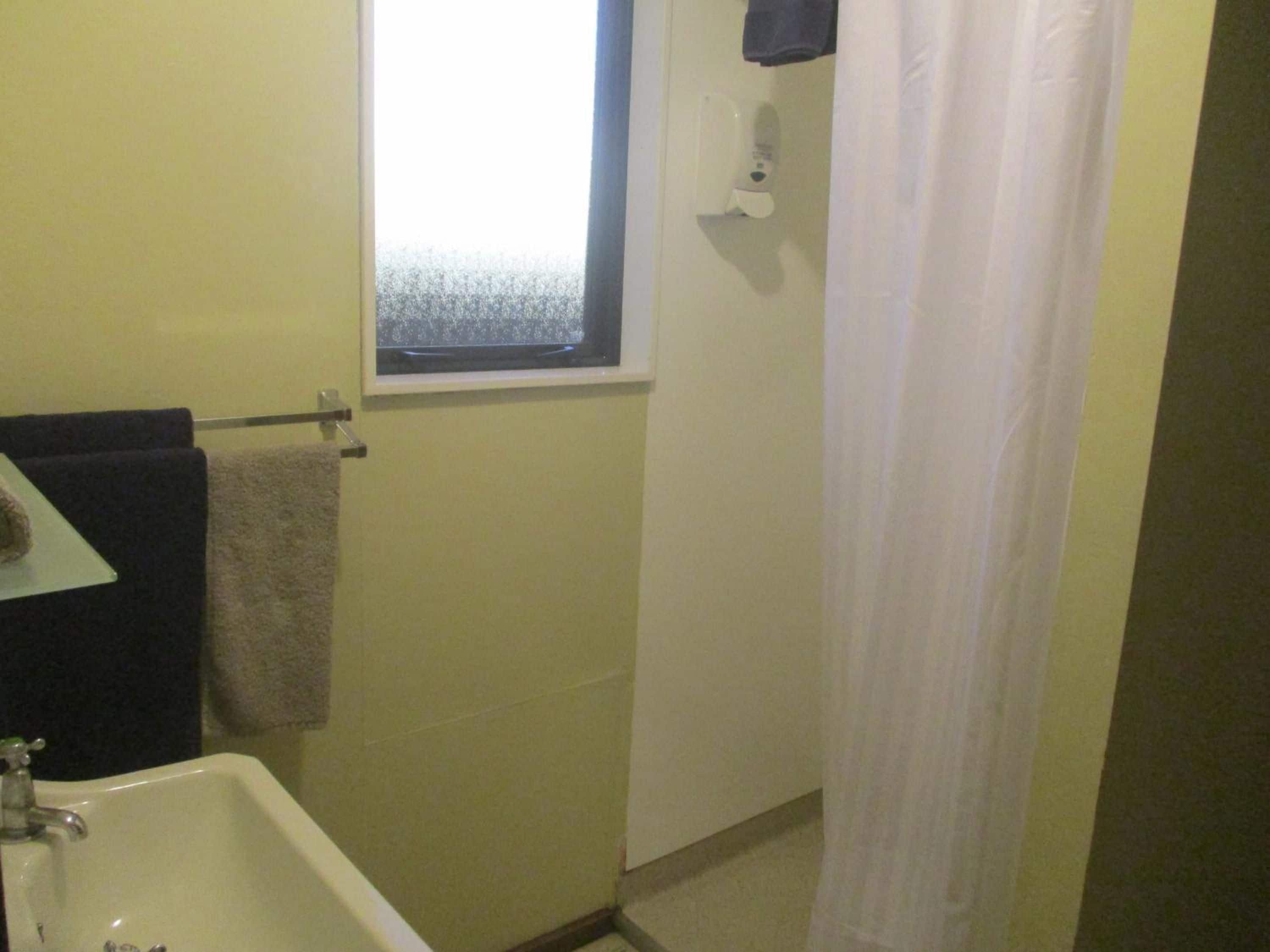 A bathroom with a bathtub, a window with frosted glass, and a towel rack.