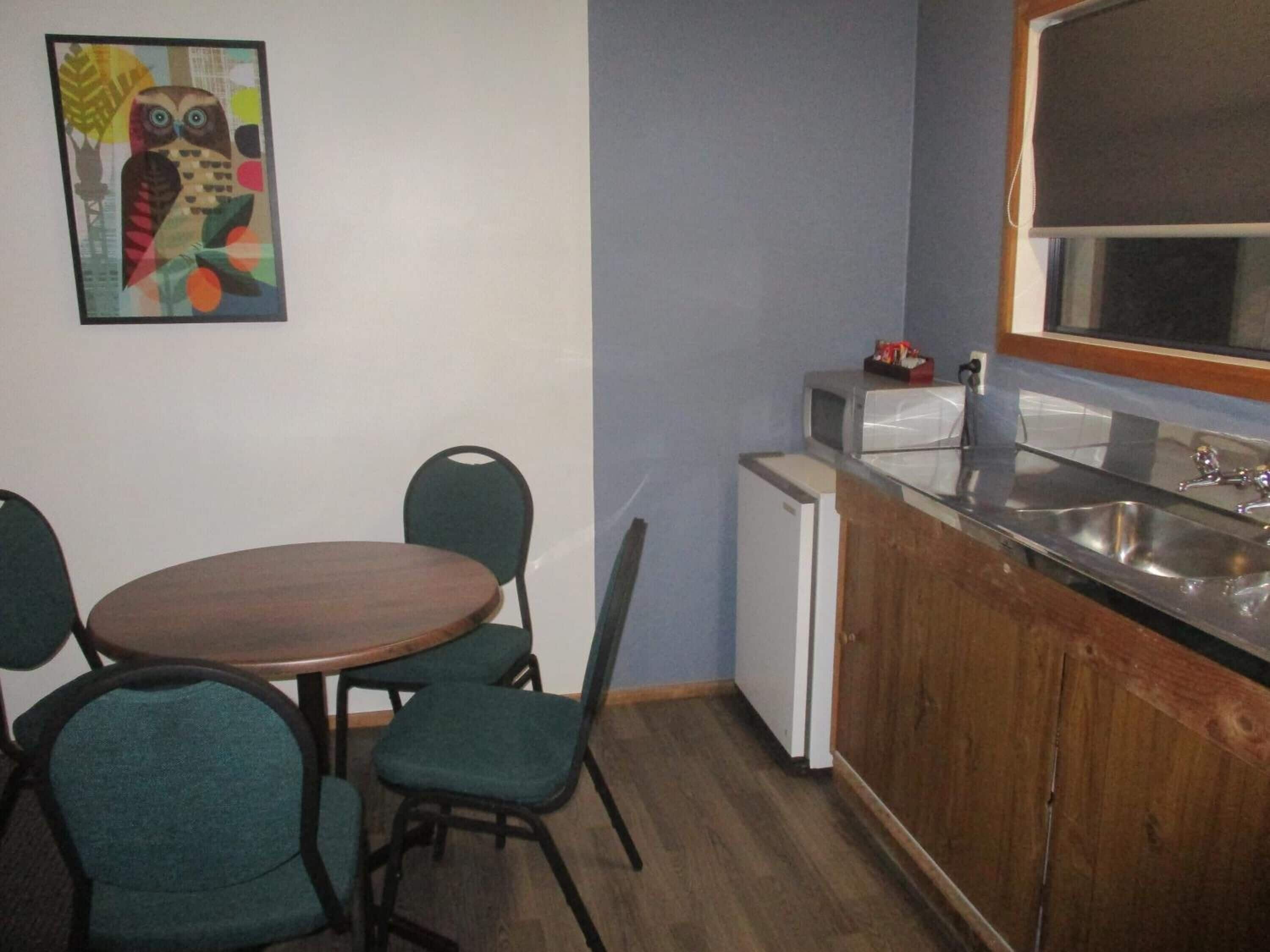 A compact kitchen with a wooden table and chairs, a small refrigerator, and a sink.