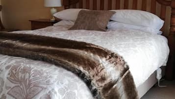 A bed with a patterned bedspread and a fur throw, a wooden headboard, and a bedside lamp.