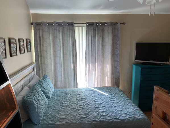 A bedroom with a bed, curtains, a television, and a dresser.