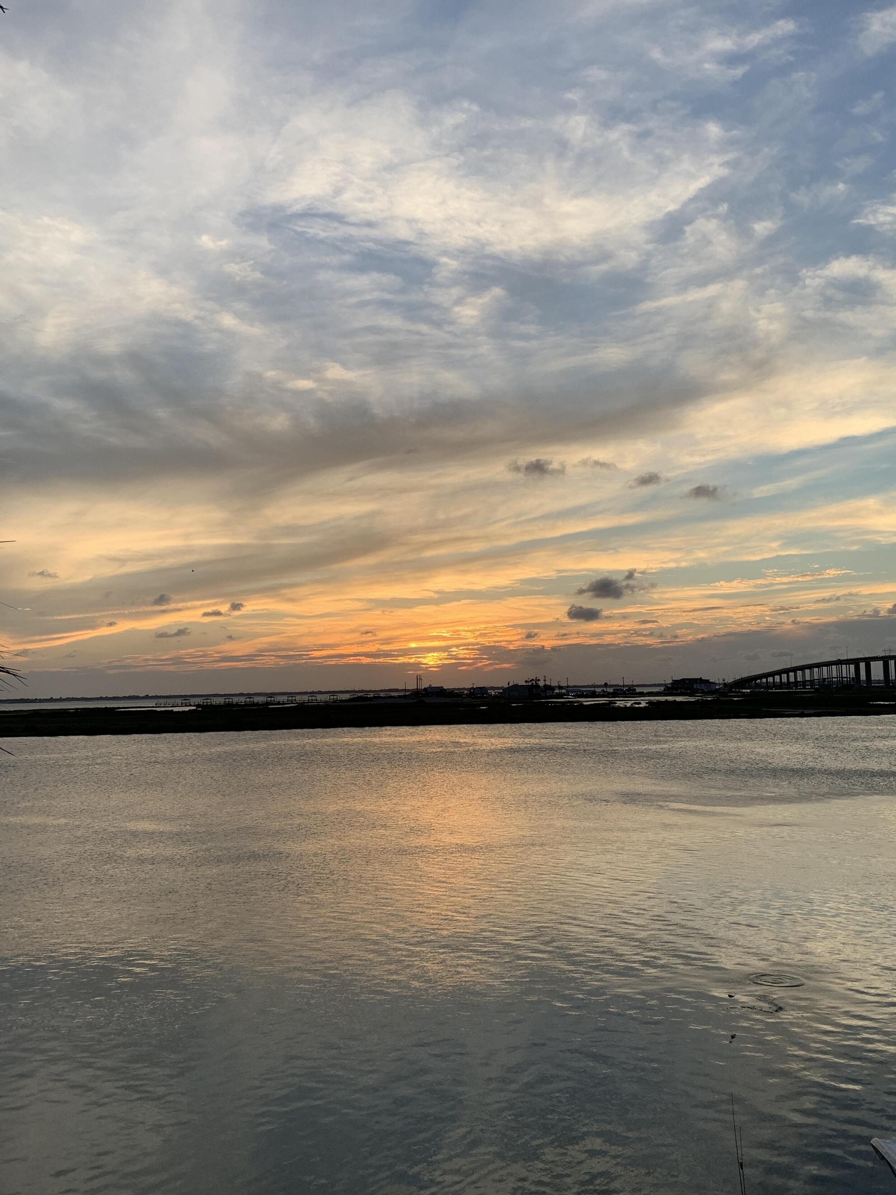 A calm body of water reflecting the sky during sunset.