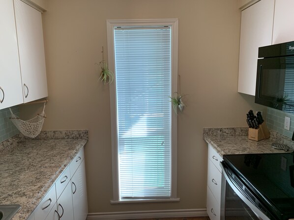 A kitchen with white cabinets, a granite countertop, a built-in oven, and a microwave.